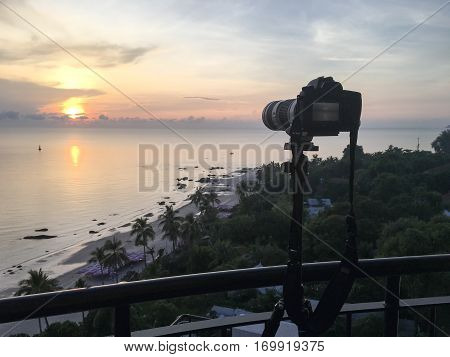 camera on tripod take sunrise picture over sea and beach at Hua Hin Thailand in warm tone