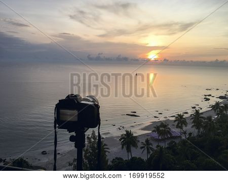 camera on tripod take sunrise picture over sea and beach at Hua Hin Thailand in warm tone
