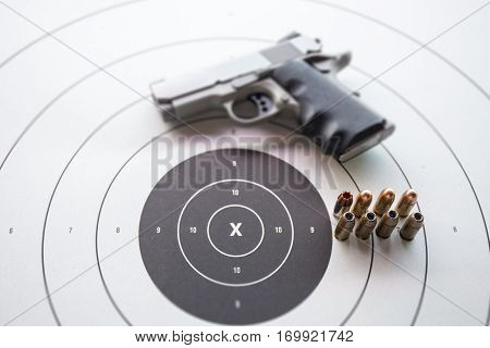 11 mm or .45 bullets on bullseye target with blurred pistol gun and copy space