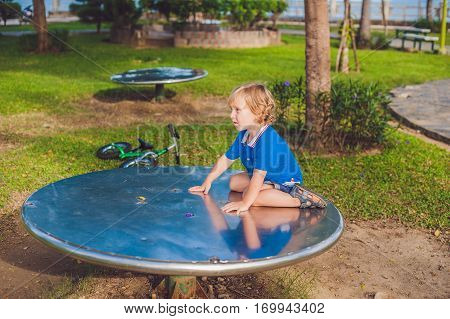 Boy Playing On The Playground In The Background Of Green Grass