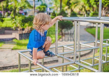 Boy Playing On The Playground In The Background Of Green Grass