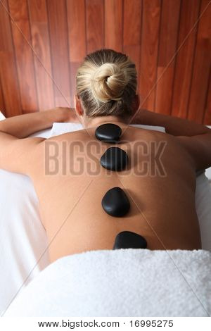 Blond kvinde håndspålæggelsen massage seng med varme sten