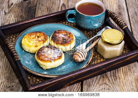 Pancakes with honey on vintage bowl on wooden tray. Studio Photo