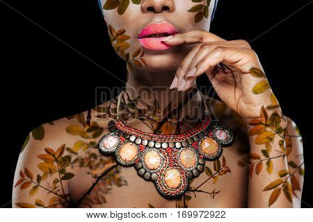 Cropped image of a attractive african woman with her hand on lips isolated on the black background