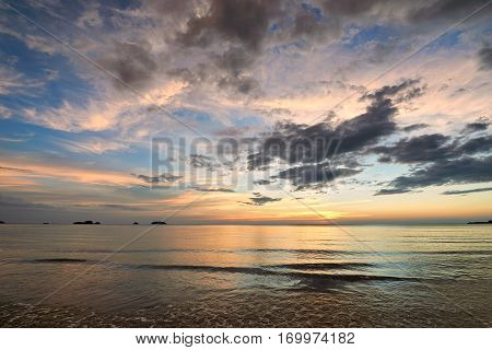 Coast of the sea at colorful sunset Koh Chang Thailand. Beach sunset is a golden sunset sky with a wave rolling to shore as the sun sets over the ocean horizon