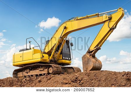 Excavator Backhoe On The Ground At Construction Site In Blue Sky Background