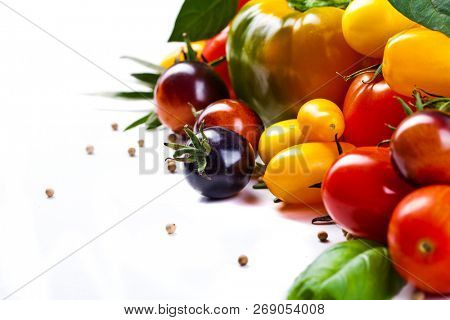 Assorted tomatoes and vegetables isolated on white background. Photo for your design