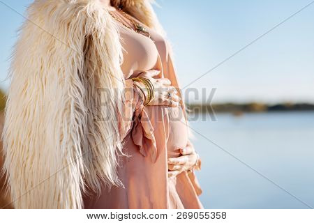 Pregnant Woman Holding Her Belly While Standing Near The Water