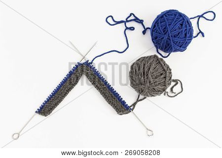 Blue And Gray Balls Of Wool With Knitting Needles On White Background