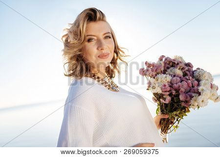 Beautiful Pregnant Woman Holding A Bunch Of Flowers