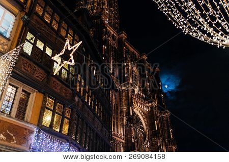View From Below To Notre-dame Cathedral And Maison Kammerzell Decorated With Christmas Lights And Fu