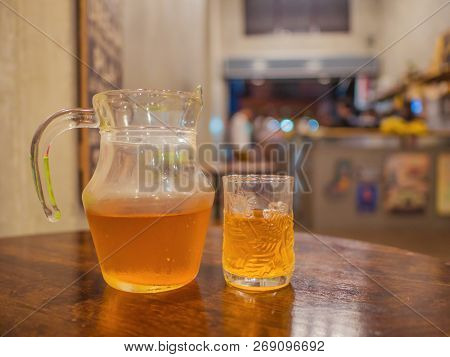 Harbal Tea In The Water Pitcher And The Glass On The Wooden Table In The Cafe