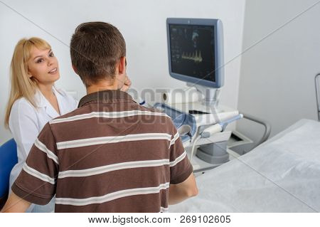 The Lady Ultrasunography Doctor Is Explaining To The Patientat Divice, In Medical Office