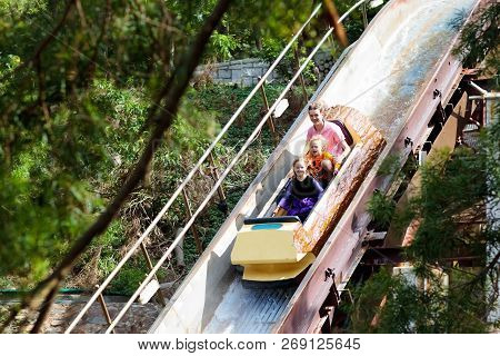 Family With Kids On Roller Coaster In Theme Park.