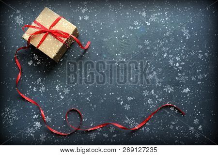 New Year And Christmas Background. Box With Red Ribbon Isolated On Black Background With Falling Sno