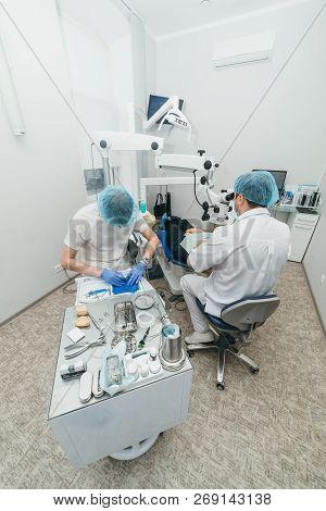 Doctor Used Microscope. Dentist Is Treating Patient In Modern Dental Office. Operation Is Carried Ou