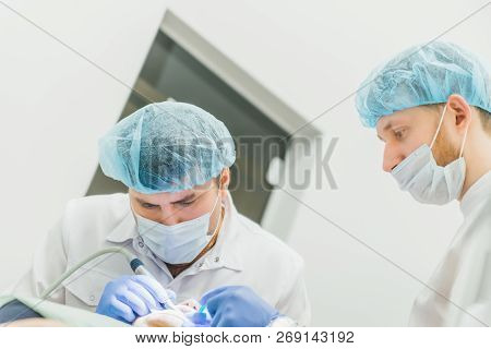 Doctor Used Microscope. Dentist Is Treating Patient In Modern Dental Office. Operation Is Carried Ou