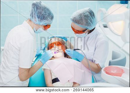 Girl Patient With Dentist And Assistant In A Dental Treatment