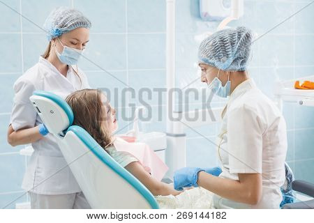 Girl Patient With Dentist And Assistant In A Dental Treatment