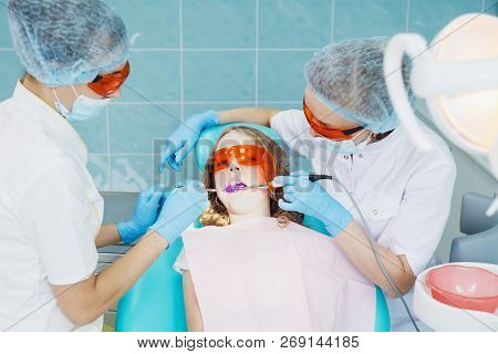 Girl Patient With Dentist And Assistant In A Dental Treatment