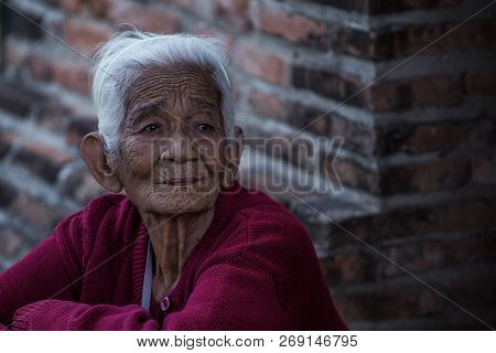 Close Up Of Old Asian Woman On Wallbrick Backgrouns