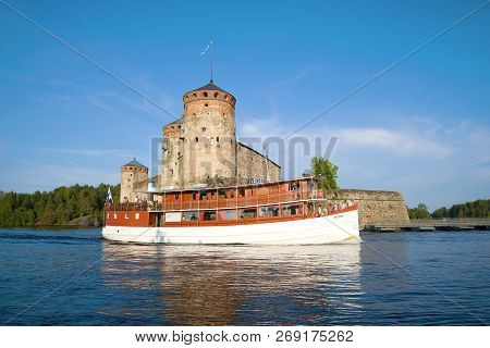 Savonlinna, Finland - July 24, 2018: A Pleasure Ship Passes By The Ancient Olavinlinna Fortress On A