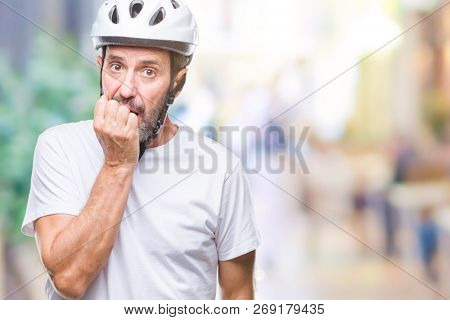 Middle age senior hoary cyclist man wearing bike safety helment isolated background looking stressed and nervous with hands on mouth biting nails. Anxiety problem.