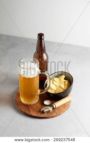 Lager Beer In Glass And Bottle With Potato Chips On Gray Concrete Background