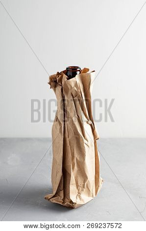 Beer Bottle In The Paper Bag On Gray Concrete Background