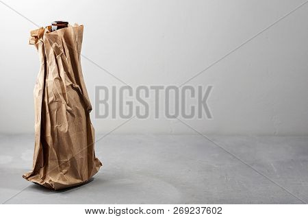Beer Bottle In The Paper Bag On Gray Concrete Background