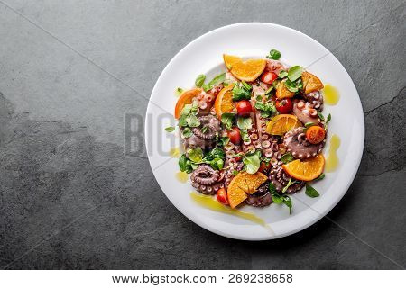 Whole Octopus Salad With Orange, Tomatoes And Cress Salad On White Plate. Top View