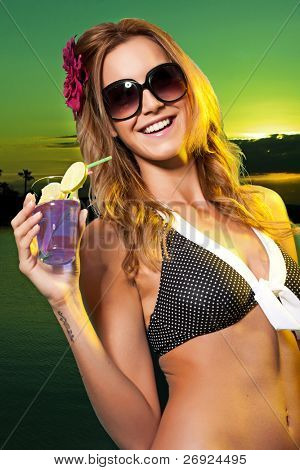 Frau trägt einen Bikini in einem Schwimmbad mit einen bunten Cocktail mit einem Regenschirm und Stroh.