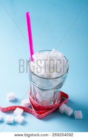 Sugar Cubes In Glass With Measuring Tape, Diabetes And Sugar Overuse Concept, Blue Background
