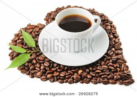 white cup with coffee beans and leaves
