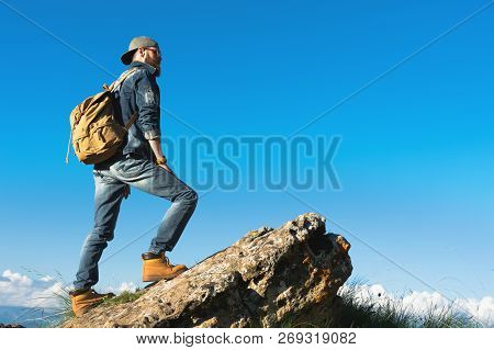 Stylish Bearded Male Traveler In Sunglasses And A Cap With A Backpack In A Denim Suit And Yellow Sho