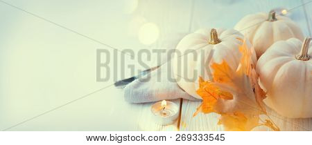 Thanksgiving Day Dinner, Served holiday table decorated with pumpkins, colorful autumn leaves and candles. Thanksgiving background, beautiful table setting. Wide screen