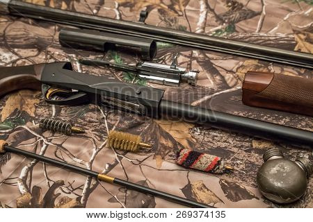 Disassembled Shotgun Parts And Cleaning Kit On The Camouflage Background