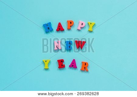 Text Happy New Year Of Bright Multicolored Wooden Letters On Blue Background. Top View Greeting Card