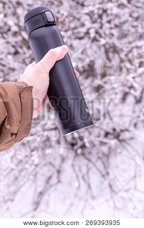 A man hold vacuum insulated bottles. Keeping drinks hot. Vertical frame. -