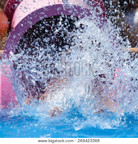 People Having Fun At Aqua Park. Lots Of Splashes Around Sliding Flume.