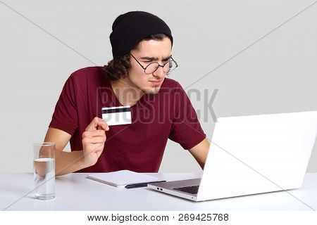 Serious Man In Black Hat, Round Glasses, Looks Scrupulously At Screen On Portable Laptop, Does Verif