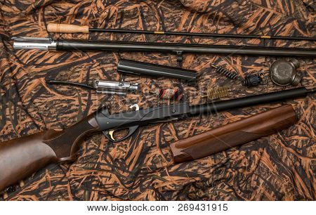 Disassembled Shotgun Parts And Cleaning Kit On The Camouflage Background