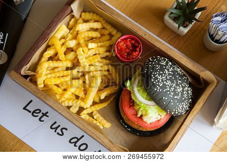 Black Colored Small Mouth-watering, Delicious Burger On The Wooden Tray Served With Red Ketchup Sauc