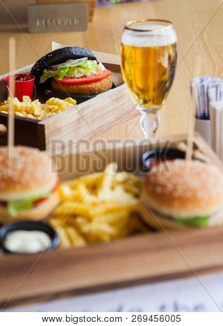 One Black Colored And Two Normal Small Mouth-watering, Delicious Burgers On The Wooden Tray Served W