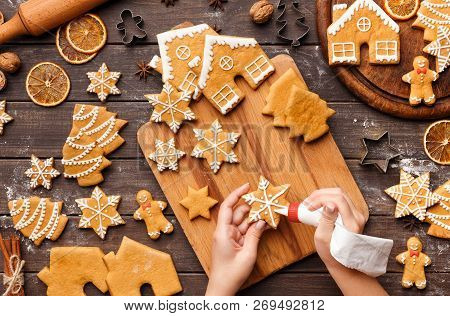 Icing Process Of Christmas Bakery. Unrecognizable Woman Decorating Homemade Gingerbread Cookies On W