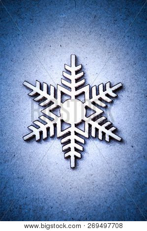 White Wooden Snowflake On Blue Craft Paper