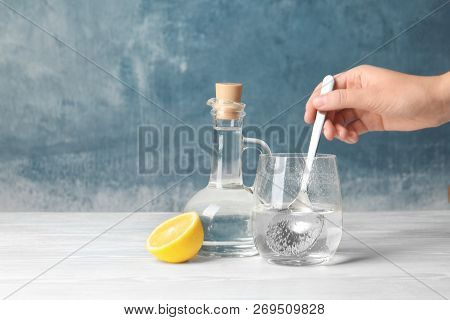Woman Mixing Vinegar And Baking Soda In Glass On Table. Space For Text