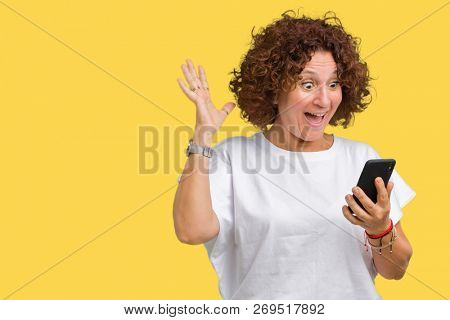 Middle ager senior woman using and texting with smartphone over isolated background very happy and excited, winner expression celebrating victory screaming with big smile and raised hands
