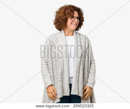 Beautiful middle ager senior woman wearing jacket and glasses over isolated background looking away to side with smile on face, natural expression. Laughing confident.