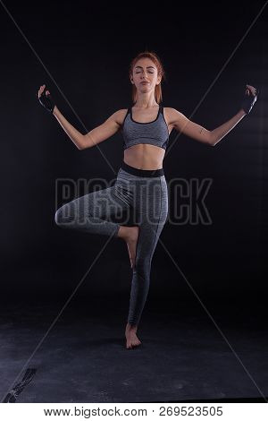 Ftiness Girl Relaxing Her Mind And Spirit In Tree Yoga Pose During Studio Photoshoot.